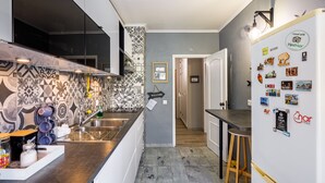 A modern kitchen with a patterned backsplash, stainless steel appliances, and a refrigerator adorned with travel magnets. - Kwadalayo Art Quarters (Faro)