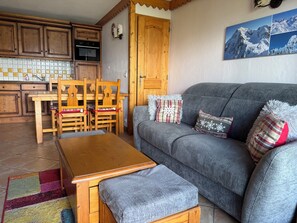 Una sala acogedora con un sofá gris, una mesa de comedor de madera y sillas.