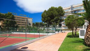 Ein Tennisplatz mit Netz, umgeben von einem Zaun, und im Hintergrund ein Gebäude mit der Aufschrift 'HOTEL JAME I'.