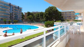 Ein Hotelpoolbereich mit einem kreisförmigen Pool, einem Tennisplatz und Blick auf die Hotelgebäude im Hintergrund.