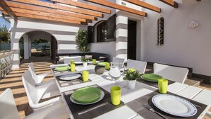 An outdoor dining area with white furniture, green plates, and yellow cups.