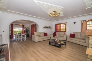 Een ruime woonkamer met twee banken, een salontafel, en een eethoek met een tafel en stoelen.