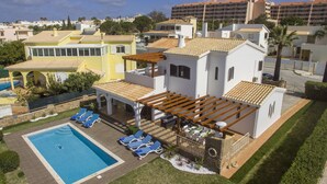 A residential property with a swimming pool, outdoor seating, and a view of surrounding buildings.