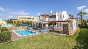 A modern villa with a swimming pool, outdoor seating, and a well-maintained garden.