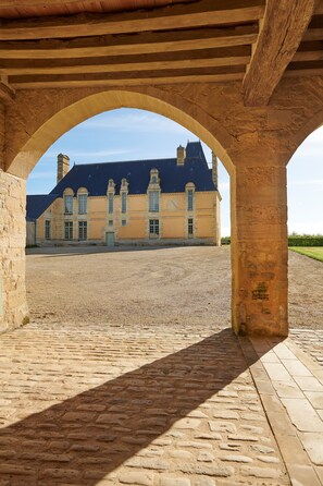Ein Innenhof mit einem großen Gebäude im Hintergrund, Steinpflaster und Holzbalken.