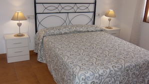 A neatly made bed with a patterned bedspread and pillows, flanked by two bedside tables with lamps.
