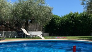 A swimming pool with a seafood paella dish and two wine glasses on the edge.