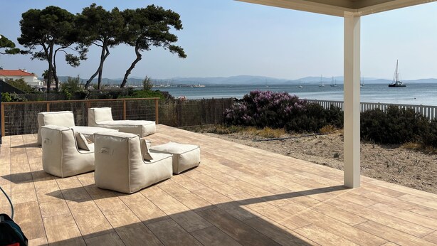 Un espacio de estar al aire libre, cubierto, con vista al mar y barcos.