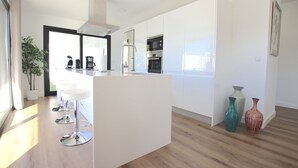 A modern kitchen with white cabinets, stainless steel appliances, and a central island with bar stools. - Beautiful Villa for 6 people, WiFi, private and heated pool, 8min from the beach (Costa Adeje)