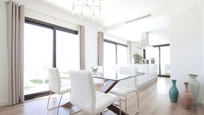 A modern kitchen with a glass dining table, white chairs, and a view of the outdoors. - Beautiful Villa for 6 people, WiFi, private and heated pool, 8min from the beach (Costa Adeje)