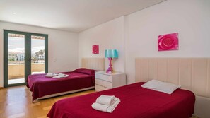 A hotel room with two beds, a small white nightstand, a colorful lamp, and two pink wall art pieces. - VilamouraSun Aquamar 110 -  Pool and Marina View (Quarteira)