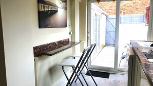 A kitchen with a marble countertop, a white radiator, a black folding chair, and a door leading to a patio. - Edwardian House in the Heart of Weymouth 200m from Sandy Beach by the Sea (Weymouth)