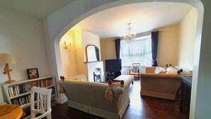 A living room with a sofa, a chair, a bookshelf, a television, and a fireplace. - Edwardian House in the Heart of Weymouth 200m from Sandy Beach by the Sea (Weymouth)