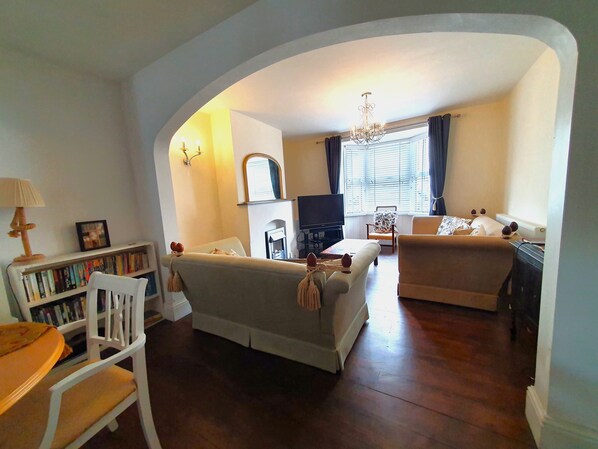 A living room with a sofa, a chair, a bookshelf, a television, and a fireplace.