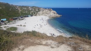 A beach with rocky terrain and a clear view of the sea.
