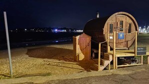 A wooden barrel structure with a sign indicating it is a 'Book Online' service, located near a beach with safety signs and a view of the sea. - Edwardian House in the Heart of Weymouth 200m from Sandy Beach by the Sea (Weymouth)