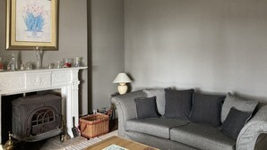 A living room with a fireplace, a sofa, a chandelier, and a framed artwork on the wall. - Detached Period Home-Former Rectory, Views Of Bristol Channel/Gower & Caldy (Narberth)