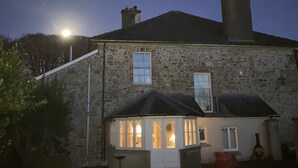 A stone building with a small attached structure, possibly a shed or garage, under a night sky with a visible moon. - Detached Period Home-Former Rectory, Views Of Bristol Channel/Gower & Caldy (Narberth)