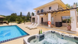 Zona de piscina con jacuzzi, sillas de descanso y una terraza con mobiliario exterior.