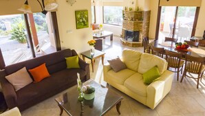 Una sala de estar con chimenea, dos sofás, una mesa de centro y un comedor con sillas y una mesa.