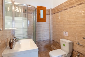 Une salle de bain avec une douche à parois de verre, un lavabo blanc et des toilettes.