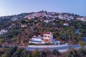 Un quartier résidentiel avec des maisons construites sur une colline, une piscine et une route.