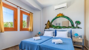 Une chambre avec deux lits, une table de chevet en bois, un miroir fixé au mur et une fenêtre avec des rideaux.