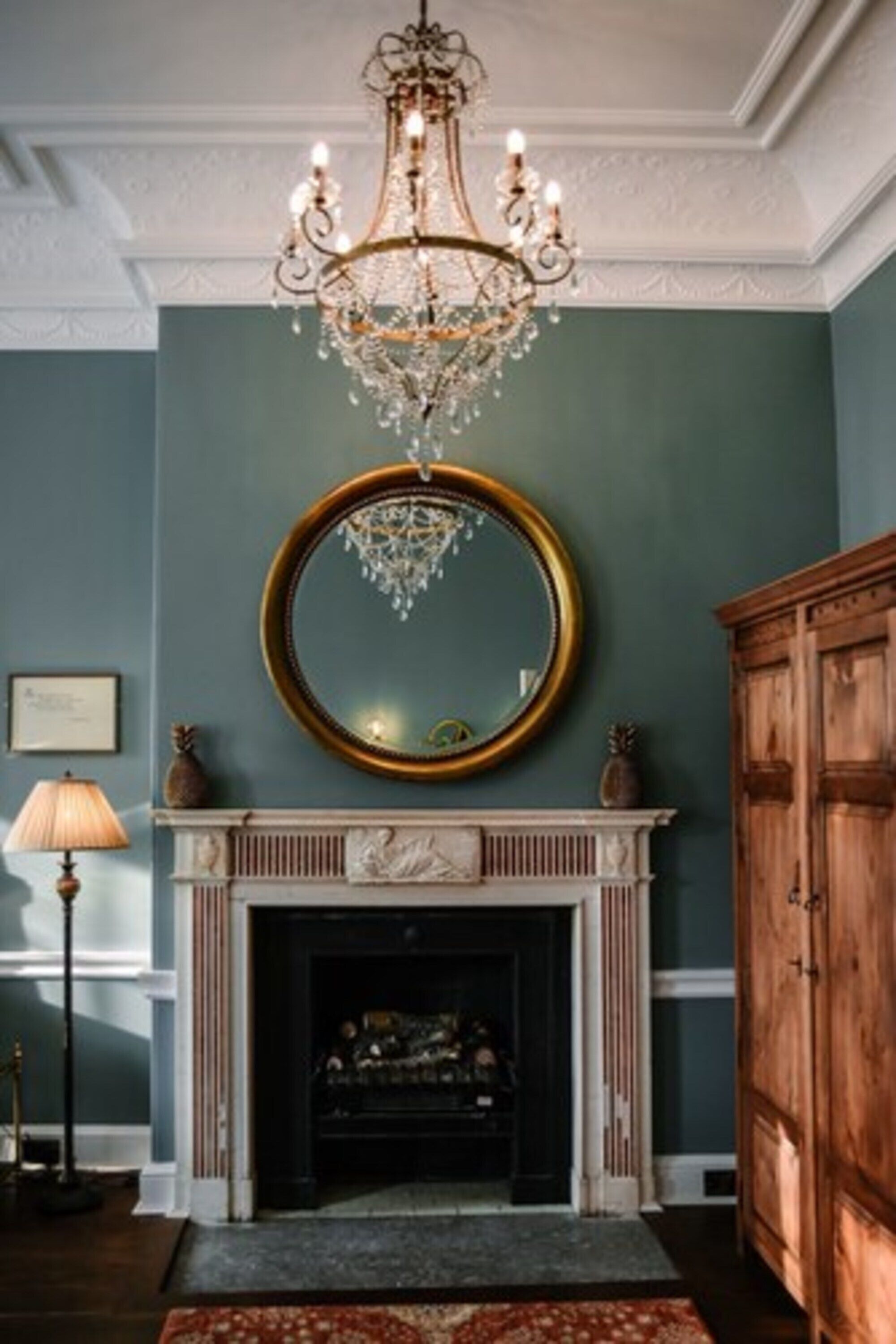 A room with a fireplace, a large mirror, and a wooden cabinet.