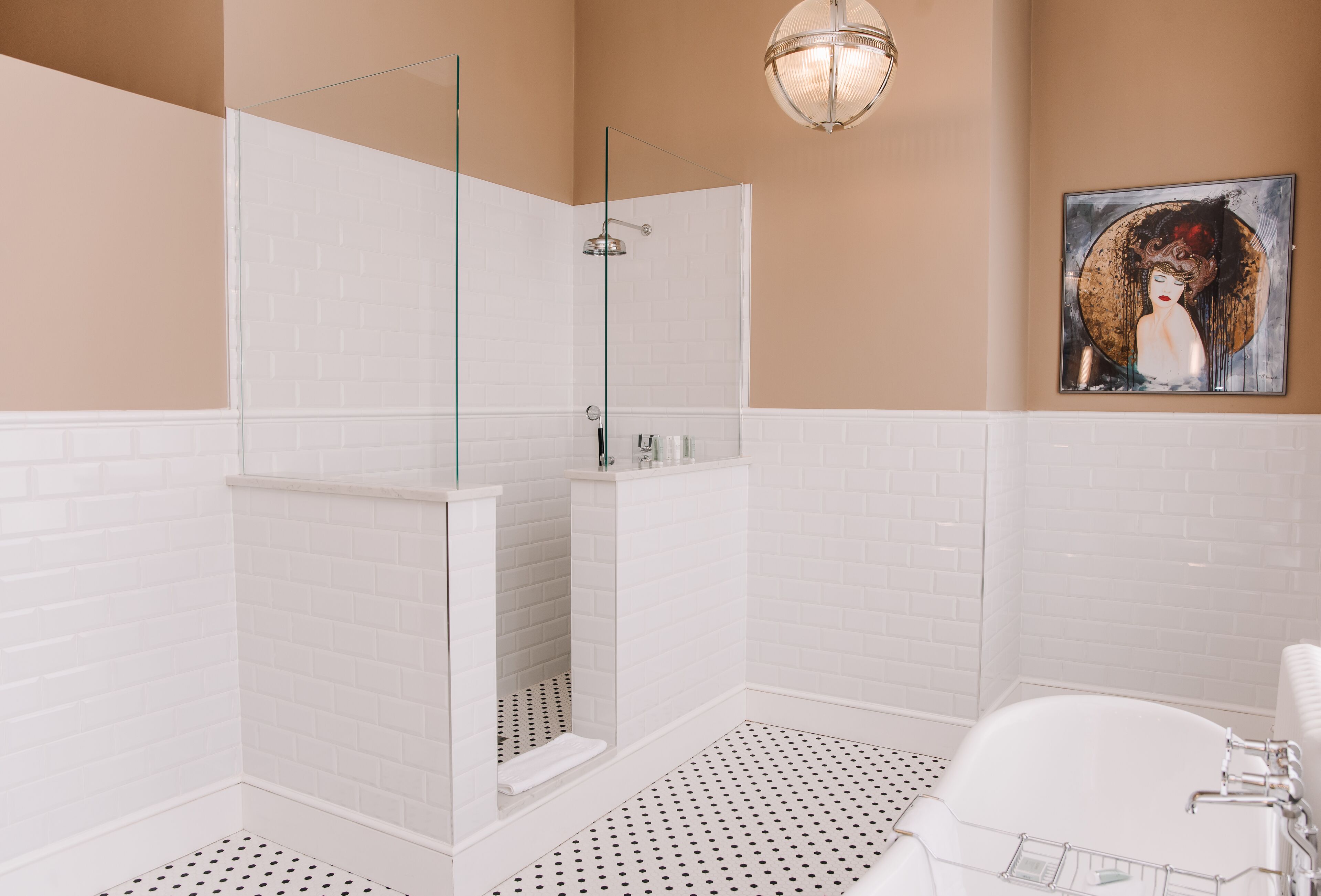 Ein modernes Badezimmer mit weißen, rechteckigen Fliesen, einer begehbaren Glasdusche, einer freistehenden Badewanne und einem zeitgenössischen Kunstwerk an der Wand.