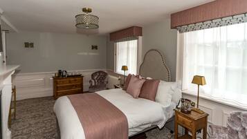 A bedroom with a large bed, a dresser, a chair, a lamp, and a window with curtains.