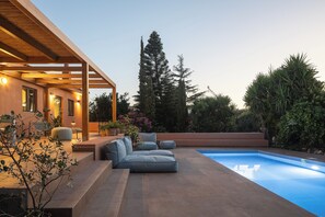 A modern outdoor pool area with a built-in seating area and a pergola structure.