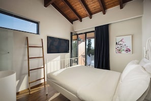 A bedroom with a bed, a ladder, a window, and a door leading to a balcony.