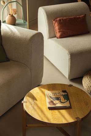 A room with a round wooden table, a beige sofa with a brown pillow, and a vase with dried flowers on a metal stand. - Villa Elli - A magical garden retreat with private pools and curated spaces (Rethymno)