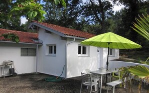 A white building with a red roof, a green umbrella, and a table with chairs. - House / Villa - LabenneStudio flat in a chalet (Labenne)