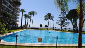 A swimming pool surrounded by palm trees and a building with balconies. - Renovated studio on the beachfront, wifi, satellite TV and air conditioning (Torremolinos)