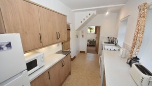 A compact kitchen with wooden cabinets, a microwave, a toaster, and a sink. - Remote Peaceful Cottage. Great for families. Panoramic Views & Skies. Fresh Air. (St. Nicholas)