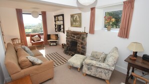 A cozy living room with a sofa, armchair, ottoman, and a stone fireplace. - Remote Peaceful Cottage. Great for families. Panoramic Views & Skies. Fresh Air. (St. Nicholas)