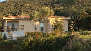 A two-story building with a tiled roof, surrounded by lush greenery and hills in the background. - Splendid villa 5 minutes from the sea (Sollacaro)
