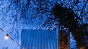 Zona de menjador a l'aire lliure amb una taula de fusta llarga preparada per a una estada, rodejada de cadires. Hi ha un xarru i una petita zona d'ambientació amb coixins.