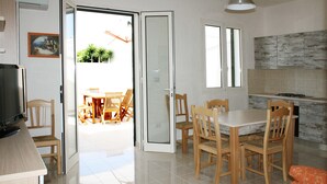 Eine moderne Küche mit Essbereich, einem Fernseher und einer Schiebeglastür, die auf eine Terrasse im Freien führt.