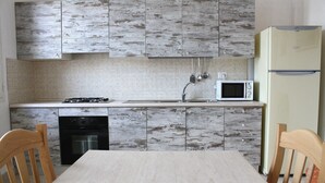 Eine Küche mit Herd, Mikrowelle, Kühlschrank und Holzschränken.