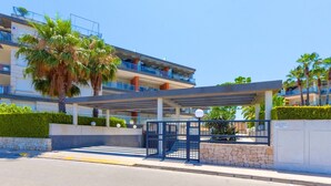 Ein moderner Hotelzugang mit überdachtem Gang, Palmen und blauem Himmel.