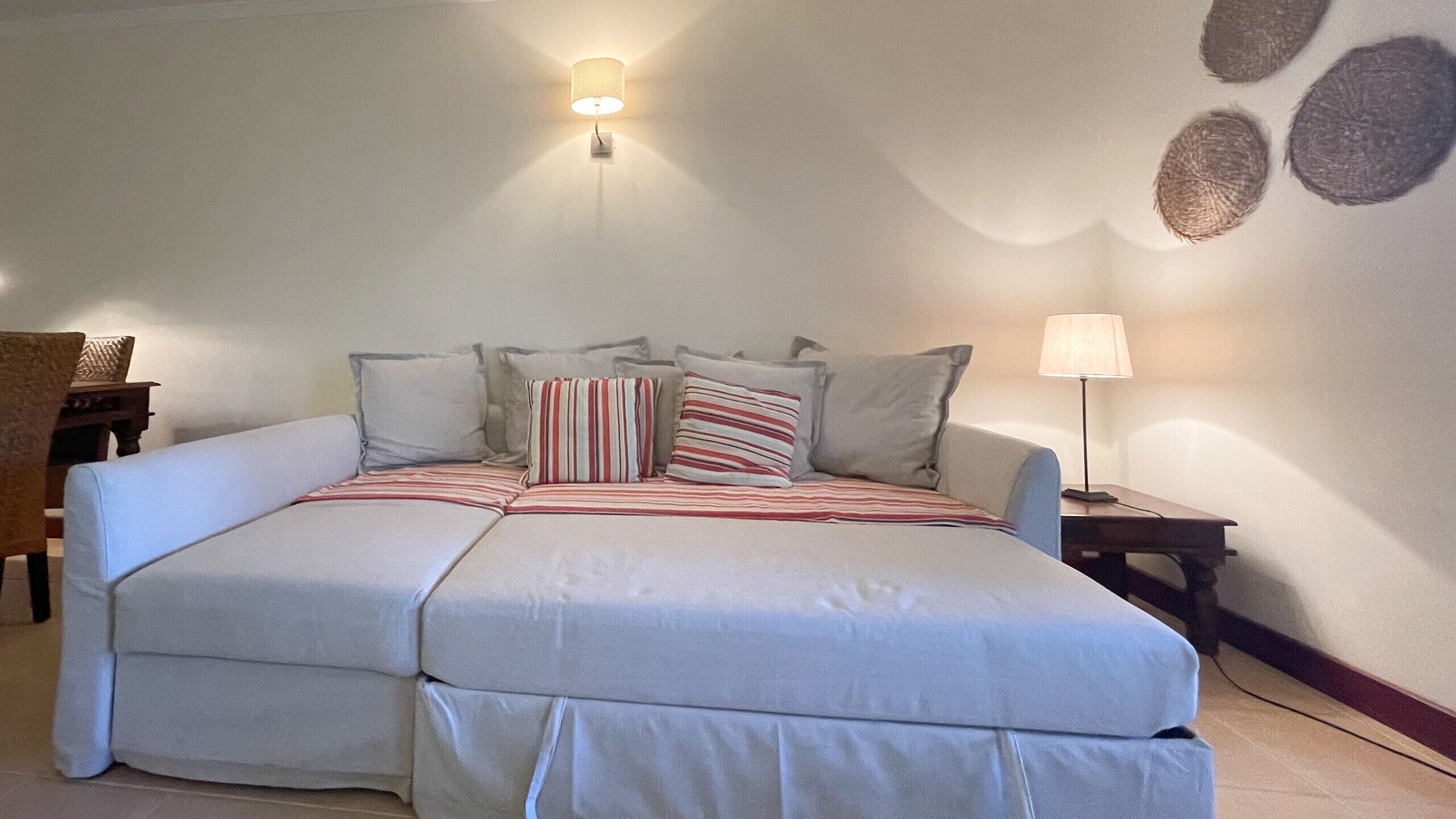 A double bed with striped bedding, a nightstand with a lamp, and a wall with circular patterns.