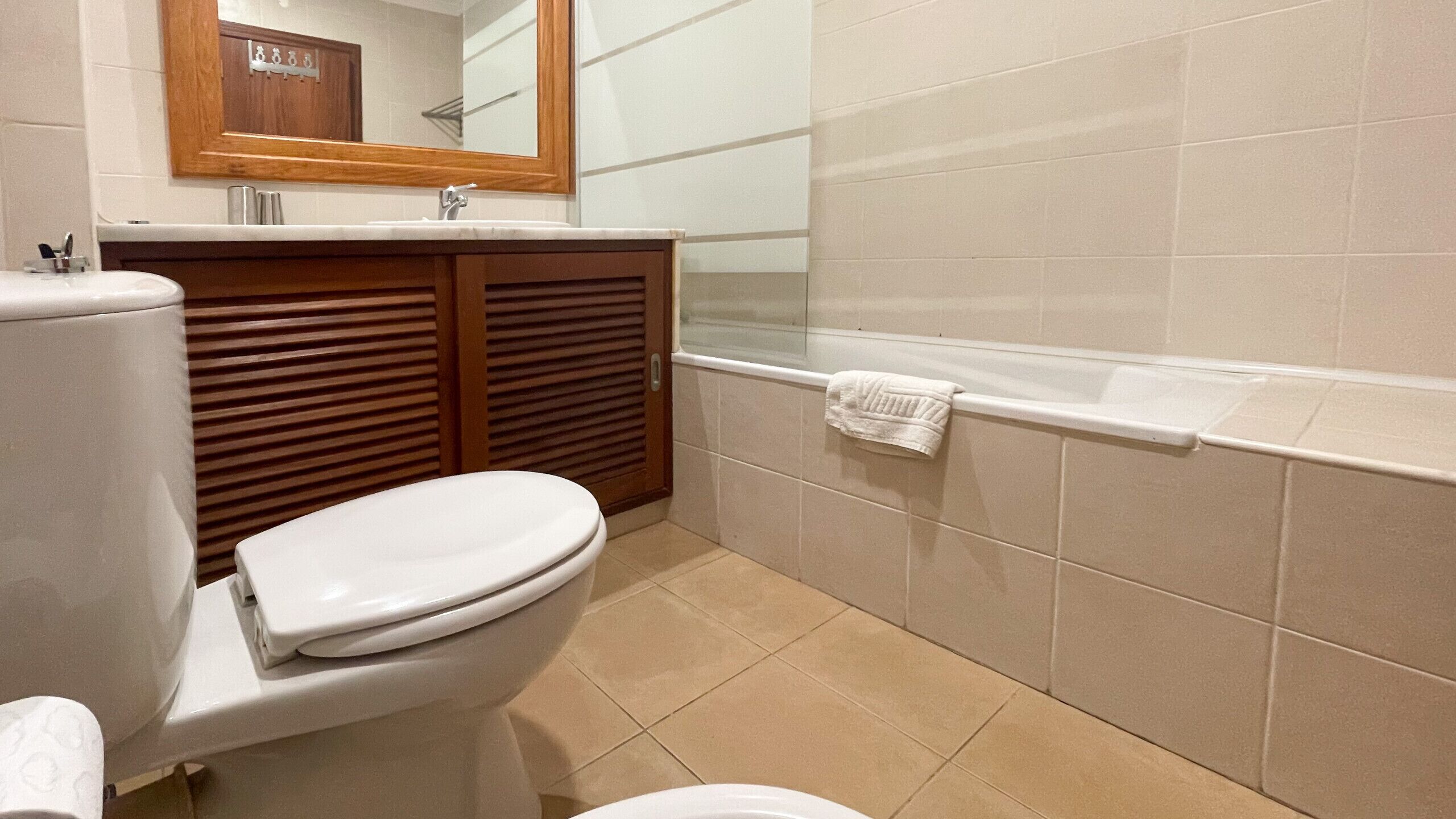 A bathroom with a toilet, a sink, a mirror, and a bathtub.