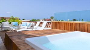 Een dakzwembad met houten terras, witte lounge fauteuils en een jacuzzi.