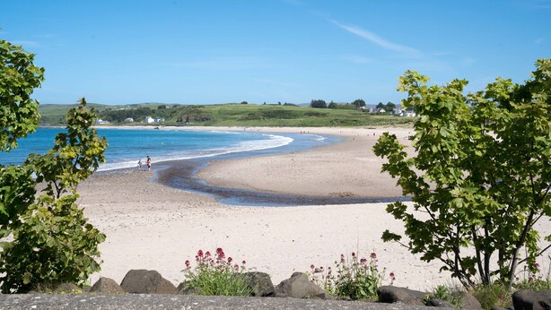 A beach with clear blue water, a sandy shore, and green hills in the background. - Forestside House - spacious house perfect for groups and families (Ballycastle)