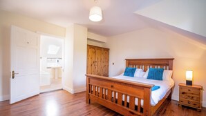 A bedroom with a wooden bed, a nightstand, a wardrobe, and a skylight. - Forestside House - spacious house perfect for groups and families (Ballycastle)