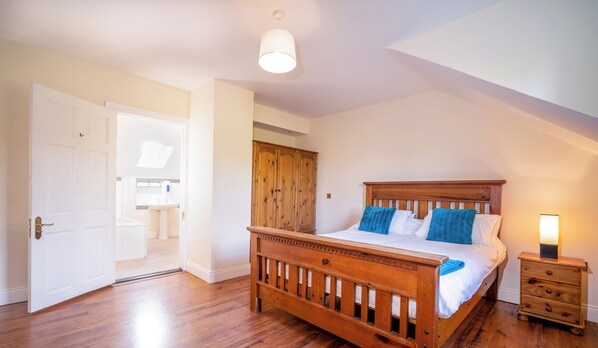 A bedroom with a wooden bed, a nightstand, a wardrobe, and a skylight.