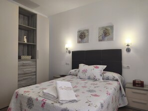 A neatly made bed with floral bedding, a bedside table with a lamp, and a wardrobe with a mirror. - Nice house with large solarium in Cordoba (Córdoba)