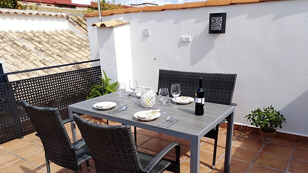 A patio with a table set for two, including plates, cutlery, glasses, and a bottle of wine. - Nice house with large solarium in Cordoba (Córdoba)